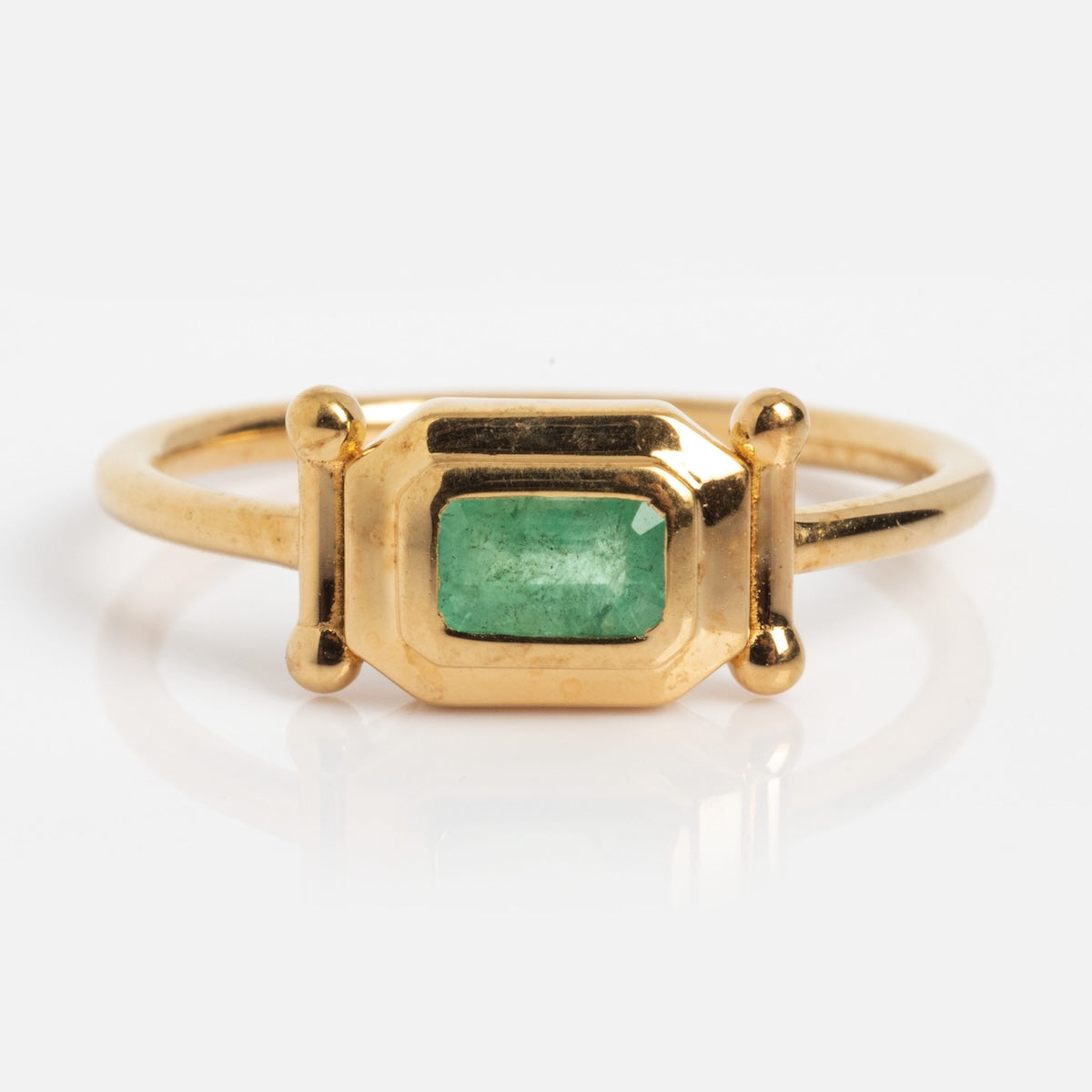 The Vintage Inspired Emerald Bar Ring Sample Size 7 features a rectangular emerald set in a geometric 14k yellow gold bezel with gold spheres on each side, shown on a white background.