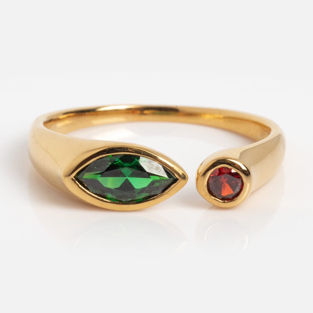 The Gem Duo Pinky Ring Sample Size 7 is a 14k gold-plated open ring, showcasing a marquise-cut green CZ on one end and a small round red CZ on the other, displayed against a white background.