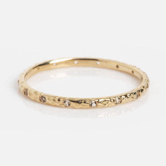 The Delicate White Topaz Stacking Ring (Sample Size 7) is a slim 1mm 9k solid yellow gold band with a hammered finish, adorned with evenly spaced small white topaz stones, shown against a white background.