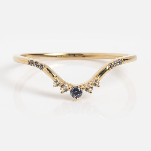 The Solid Gold Delicate Tanzanite Curve Ring Sample Size 7 is crafted in 9k yellow gold with a gentle V-shape, showcasing a central round Lab Tanzanite accented by small white topaz and blue stones on the band.