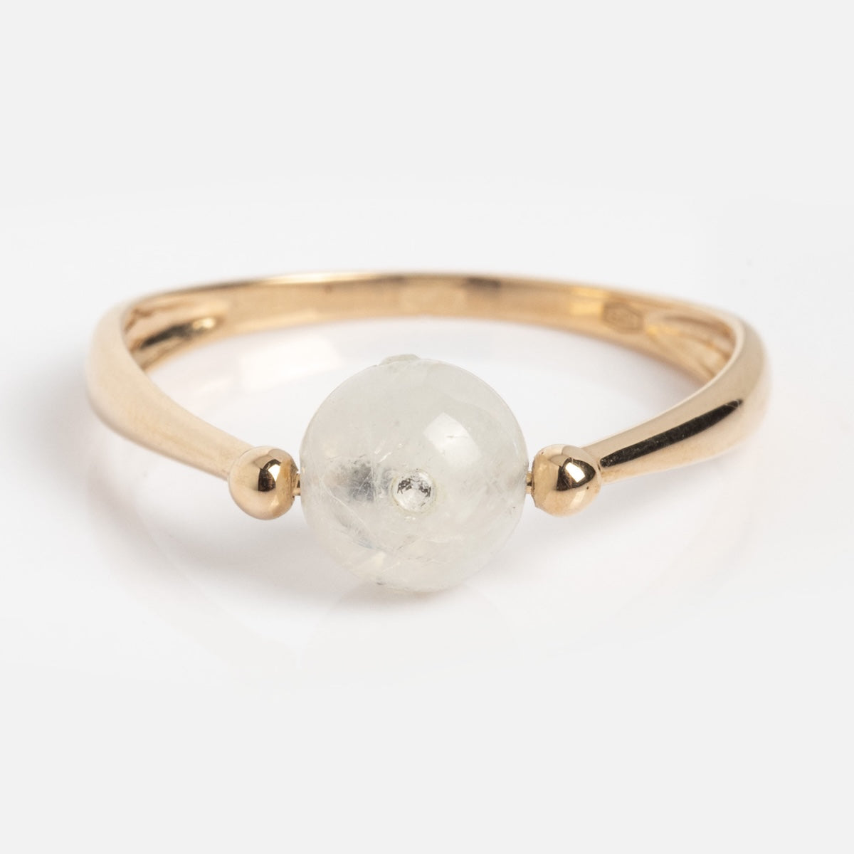 The Solid Gold Moonstone Gem Drop Ring Sample Size 7 is a 9k yellow gold ring with a round, translucent moonstone between two small gold beads on a polished band, shown on a white background.