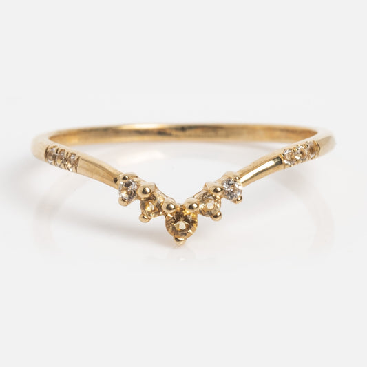 The Solid Gold Delicate Citrine Arch Ring, shown in sample size 7, features a subtle V-shaped yellow gold band accented with small round citrine stones along the band and clustered at the center against a white background.