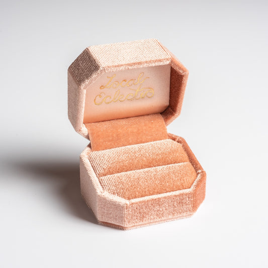 The Fancy Velvet Ring Box is pink, octagonal, and velvet with an open lid displaying “Local Eclectic” in gold inside. Featuring a cushioned slot, it's ideal for gifting or as a custom ring box, shown against a plain white background.
