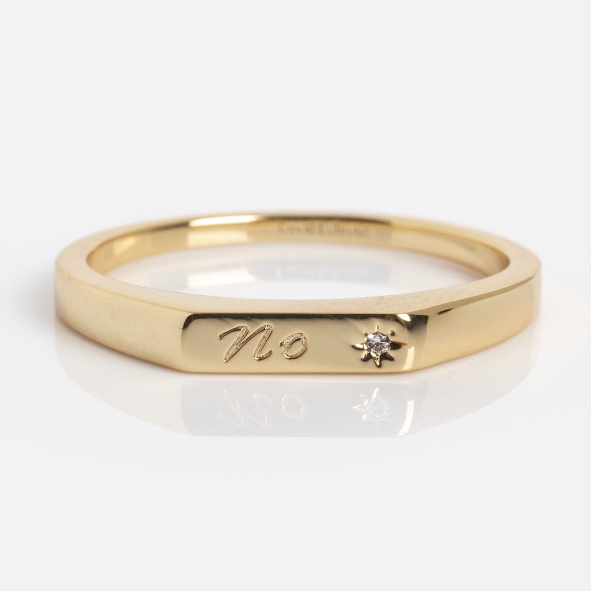The Tiny Conversation Stacking Ring features the engraved word "No" beside a small diamond, displayed on a plain white background.