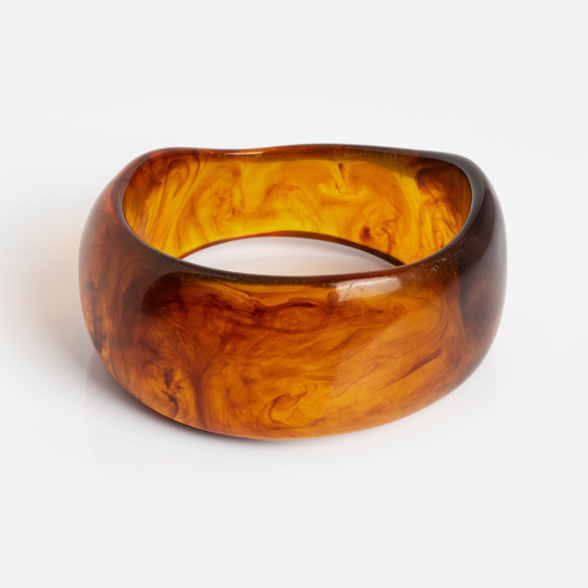 The Bangle Bracelet features a wide, translucent amber band with swirling orange and brown patterns, shown against a white background.