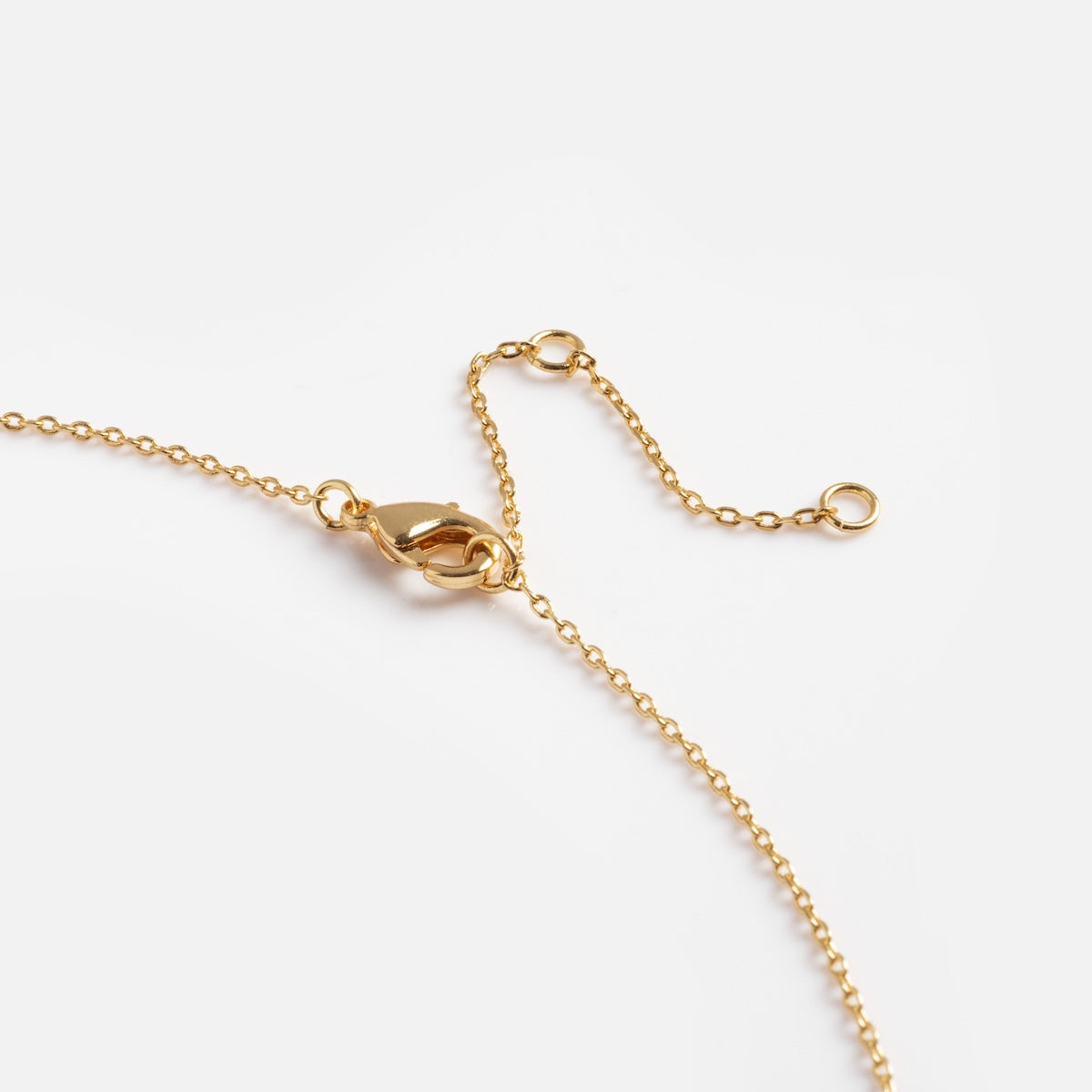 A close-up of the Celestina Starburst Necklace, featuring a delicate gold starburst design with a lobster clasp and two looped ends, set against a plain white background.