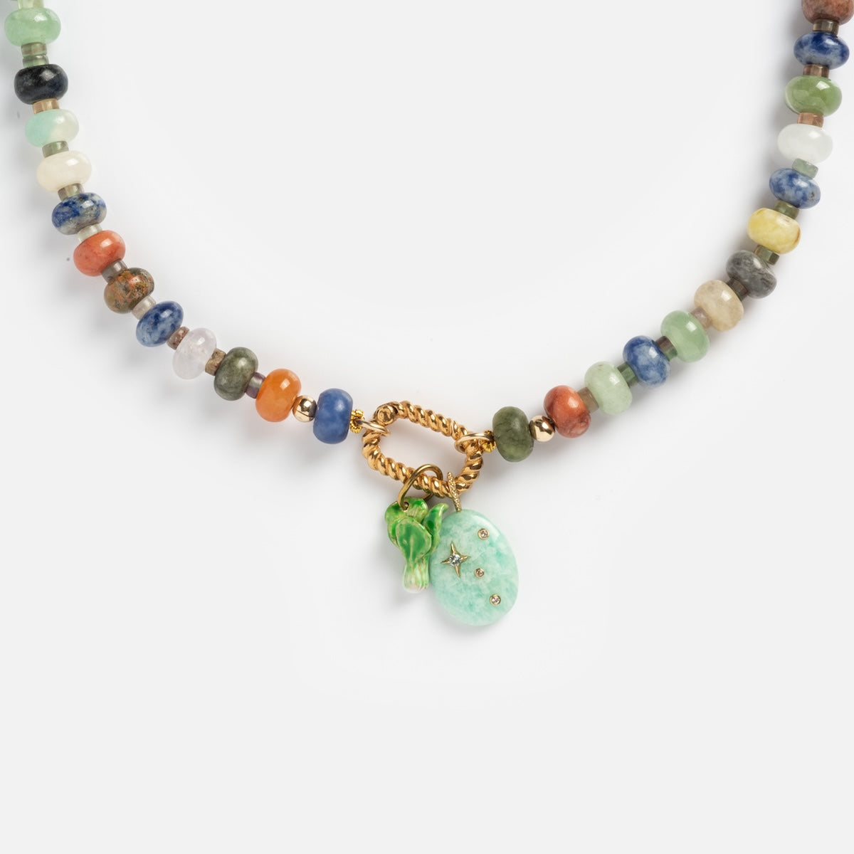 The Macey Customizable Beaded Charm Holder Necklace features colorful beads, a gold clasp, a small green glass pendant, and an oval turquoise charm with star accents.