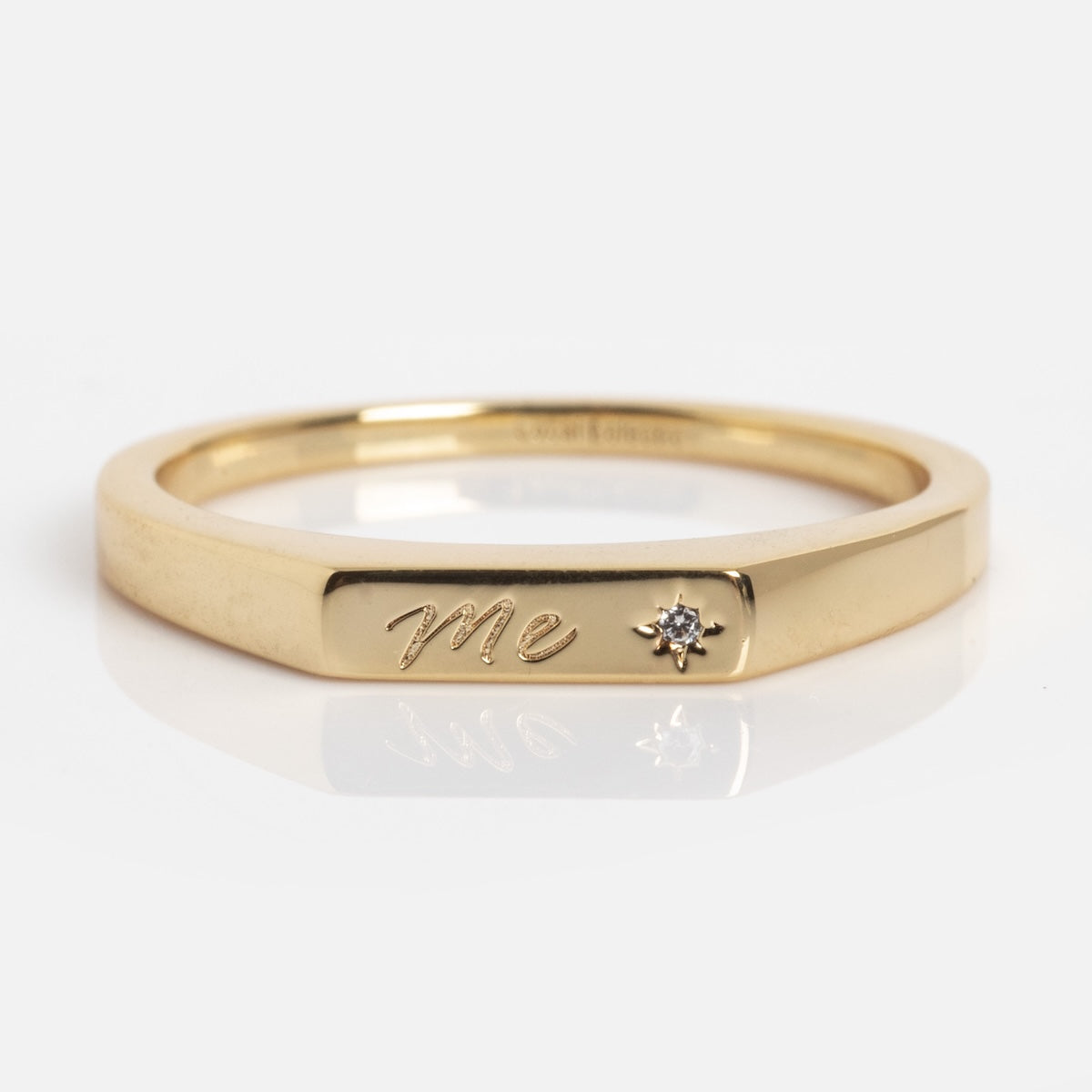 The Tiny Conversation Stacking Ring features "Me" engraved on the front and a small diamond set beside the engraving, shown against a white background.