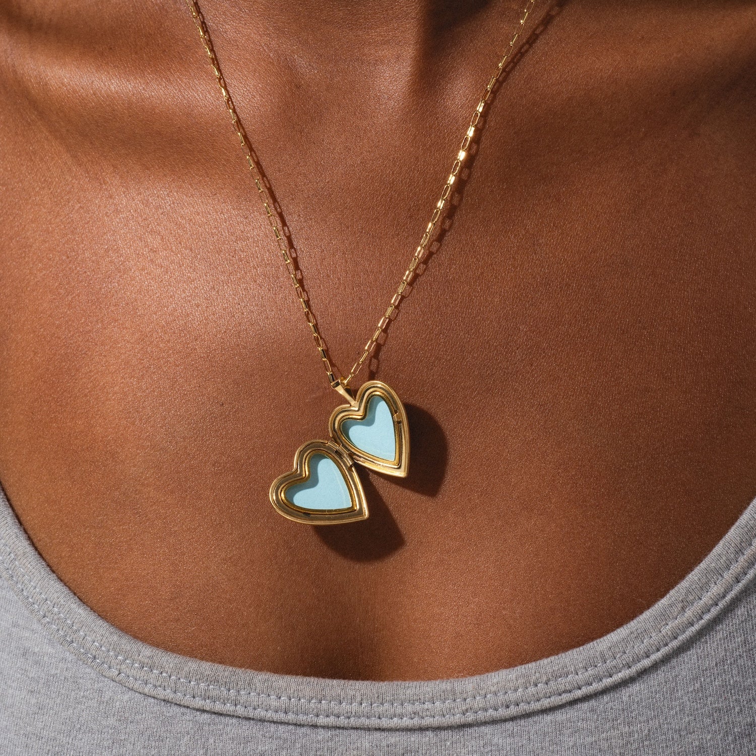 Necklace with heart-shaped pendants on a person wearing a gray top.