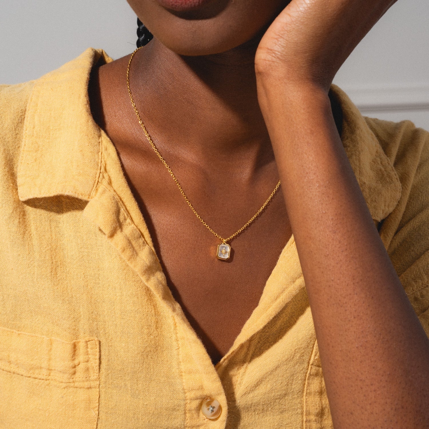 A woman in a textured yellow shirt showcases the Rainbow Moonstone & Diamond Manifest Your Dreams Pendant Necklace, featuring a rectangular pendant. The focus is on her jewelry and shirt, with her face partially out of frame.