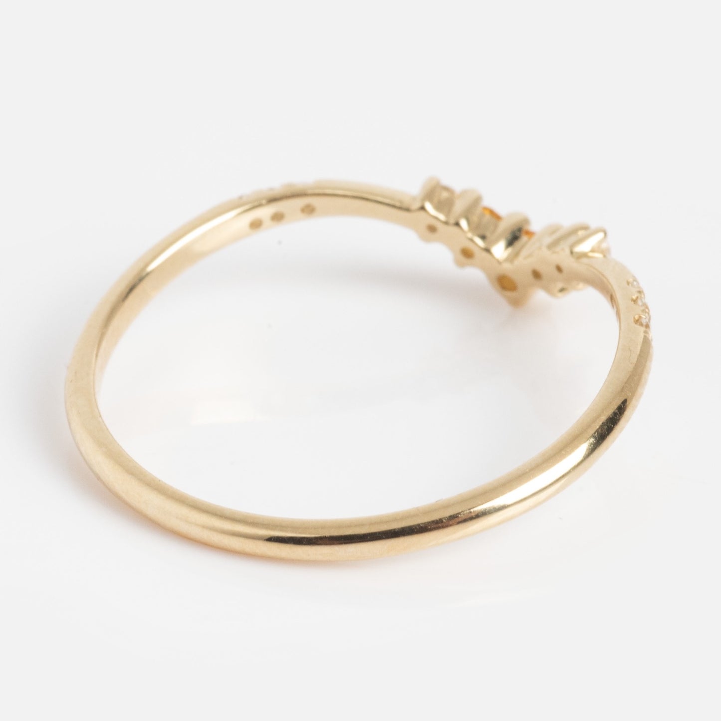 The Solid Gold 2025 November Capsule Delicate Arch Citrine Stacking Ring features a minimalist, thin gold band with a small chevron accent and a citrine, shown on a white background.