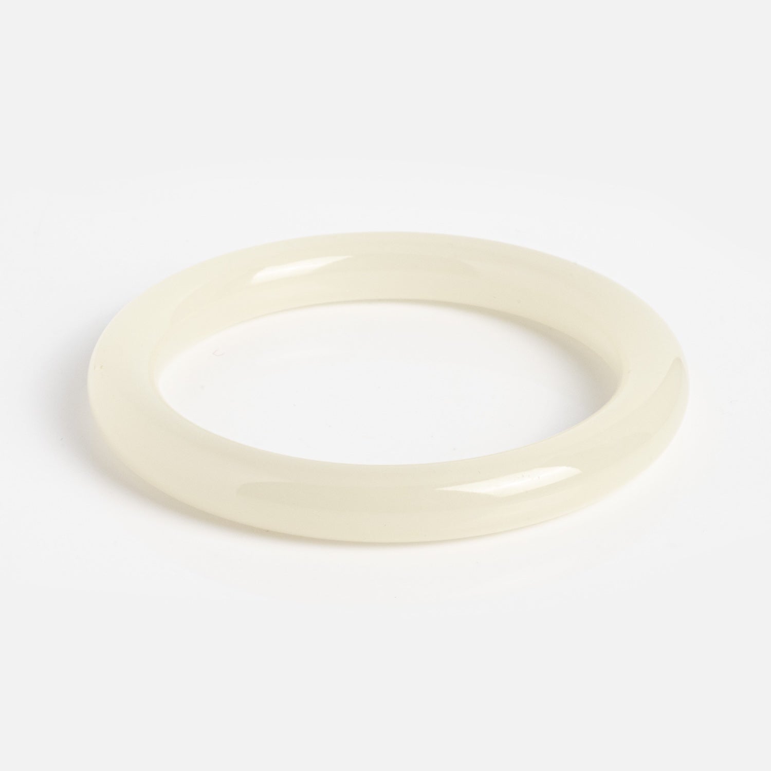 The 1994 Off White Thin Jade Bangle is a glossy, off-white round bangle with a smooth surface, expertly crafted from natural jade and shown on a plain white background.
