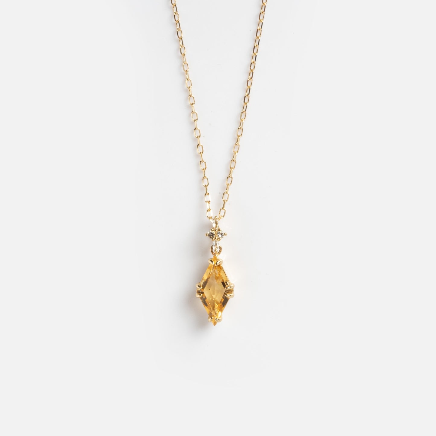 The Solid Gold 2025 November Capsule Art Deco Citrine Pendant Necklace showcases a marquise-cut yellow citrine pendant with a small round crystal above it on a delicate gold chain, displayed on a plain white background.