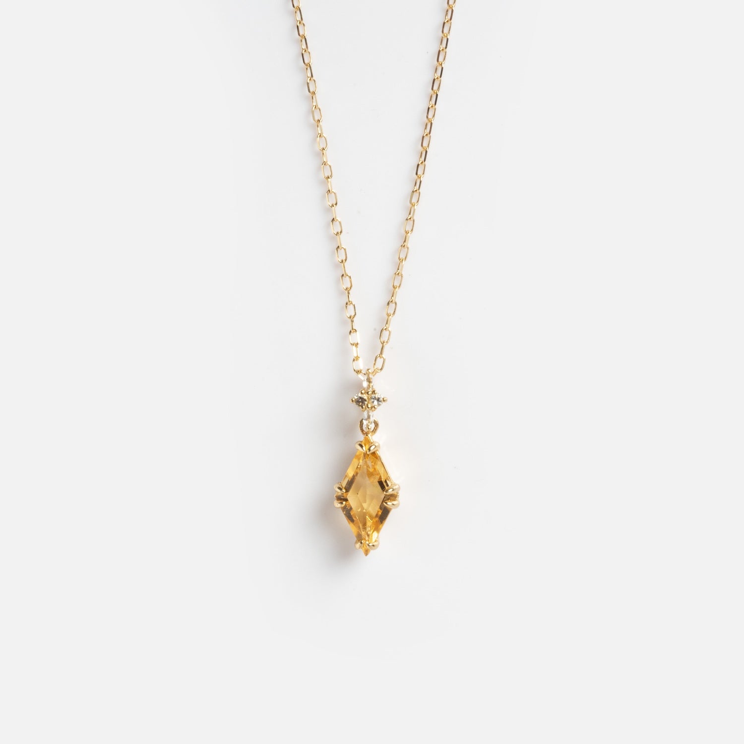 The Solid Gold 2025 November Capsule Art Deco Citrine Pendant Necklace showcases a marquise-cut yellow citrine pendant with a small round crystal above it on a delicate gold chain, displayed on a plain white background.