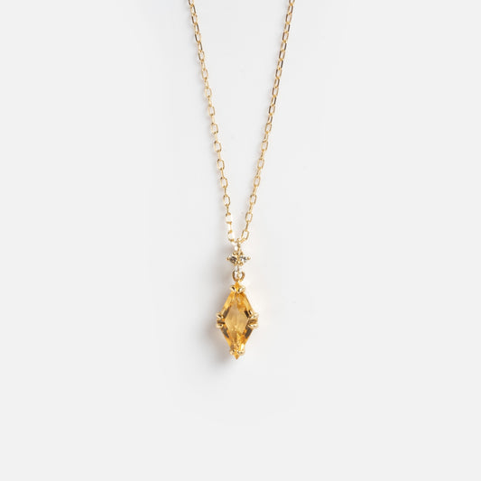 The Solid Gold 2025 November Capsule Art Deco Citrine Pendant Necklace showcases a marquise-cut yellow citrine pendant with a small round crystal above it on a delicate gold chain, displayed on a plain white background.