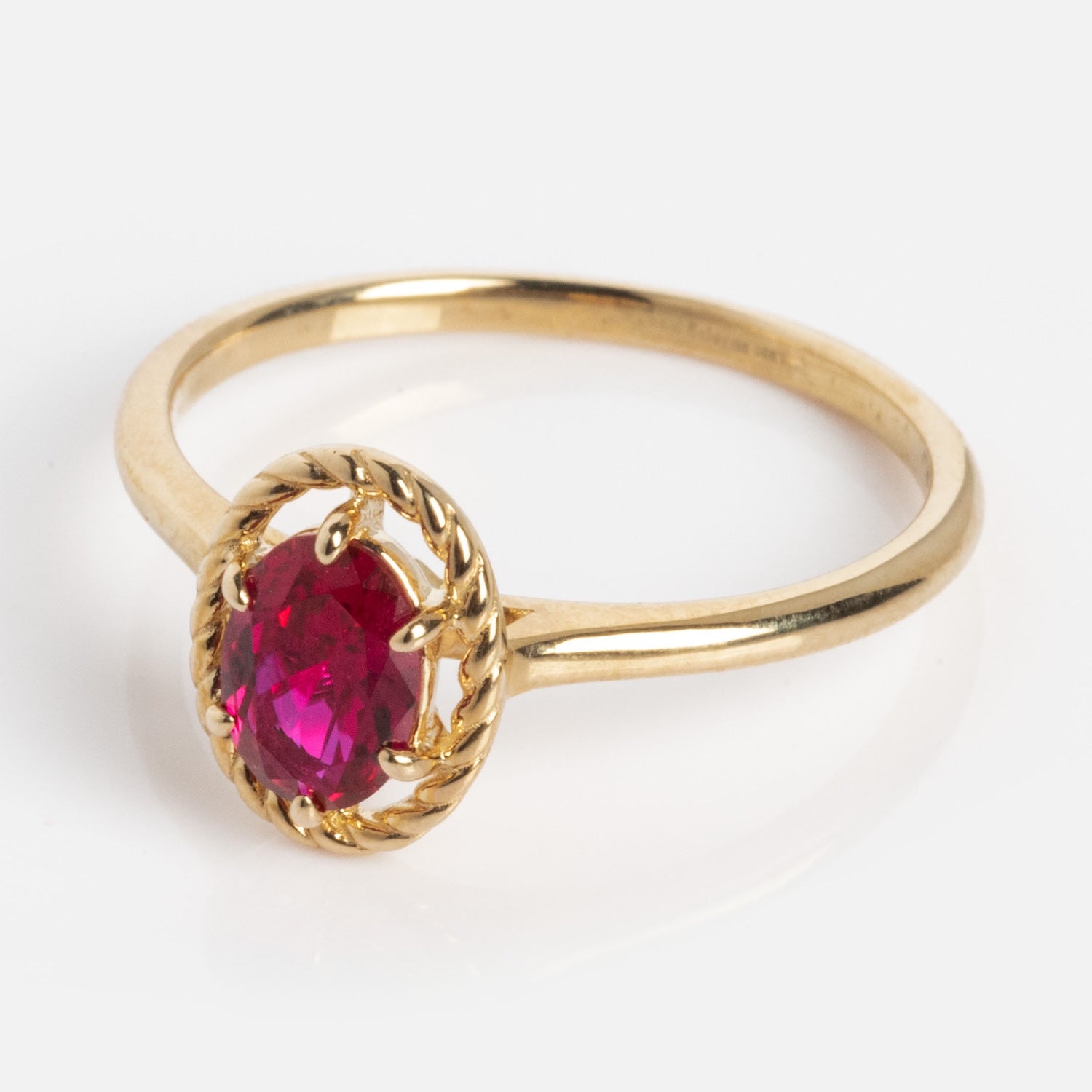 The 10k Lucky In Red Ruby Halo Ring features a round, faceted red ruby in a decorative prong setting, showcased against a white background.