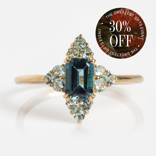 The 10k Snow Queen Blue Topaz Cluster Ring in solid yellow gold features a rectangular London blue topaz with light blue accent stones and is shown next to a "30% OFF - The Sweetest Gifts Event" circular label.