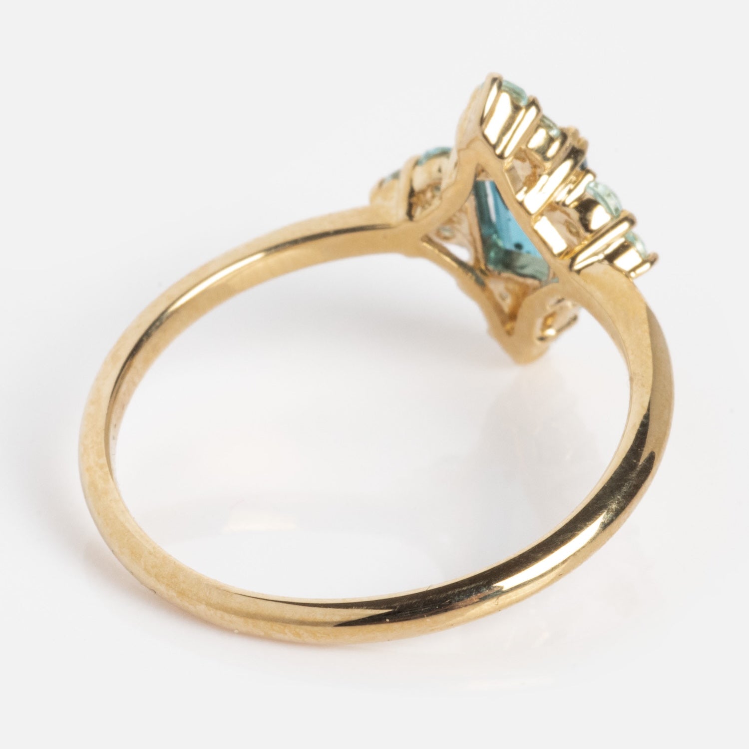 The 10k Snow Queen Blue Topaz Cluster Ring features a thin gold band and a raised setting with a light blue gemstone, shown in a side view on a white background.