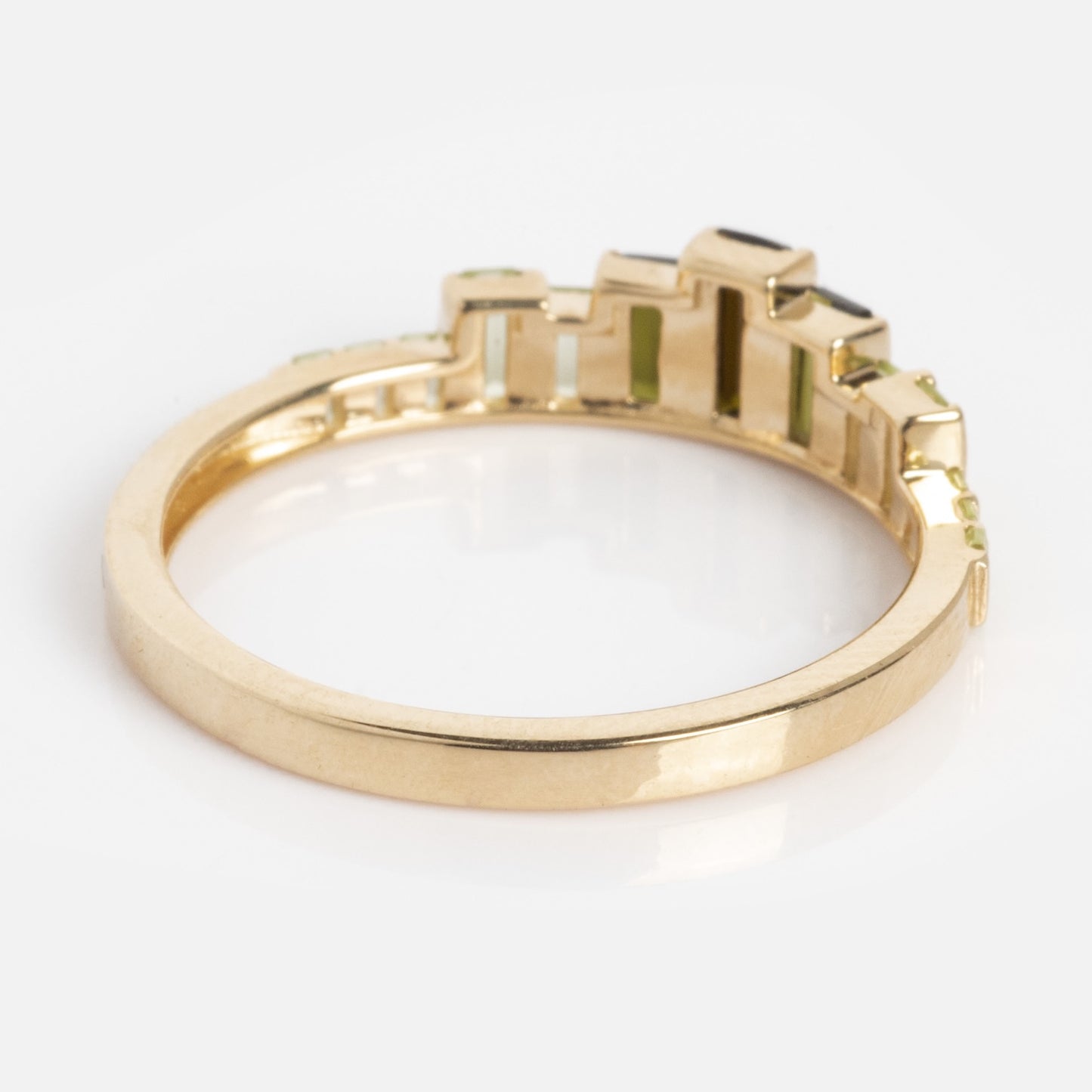 The 10k Green Tourmaline Skyline Band showcases a row of rectangular green tourmalines in a stepped geometric pattern across the top, set in gold and displayed on a white background.