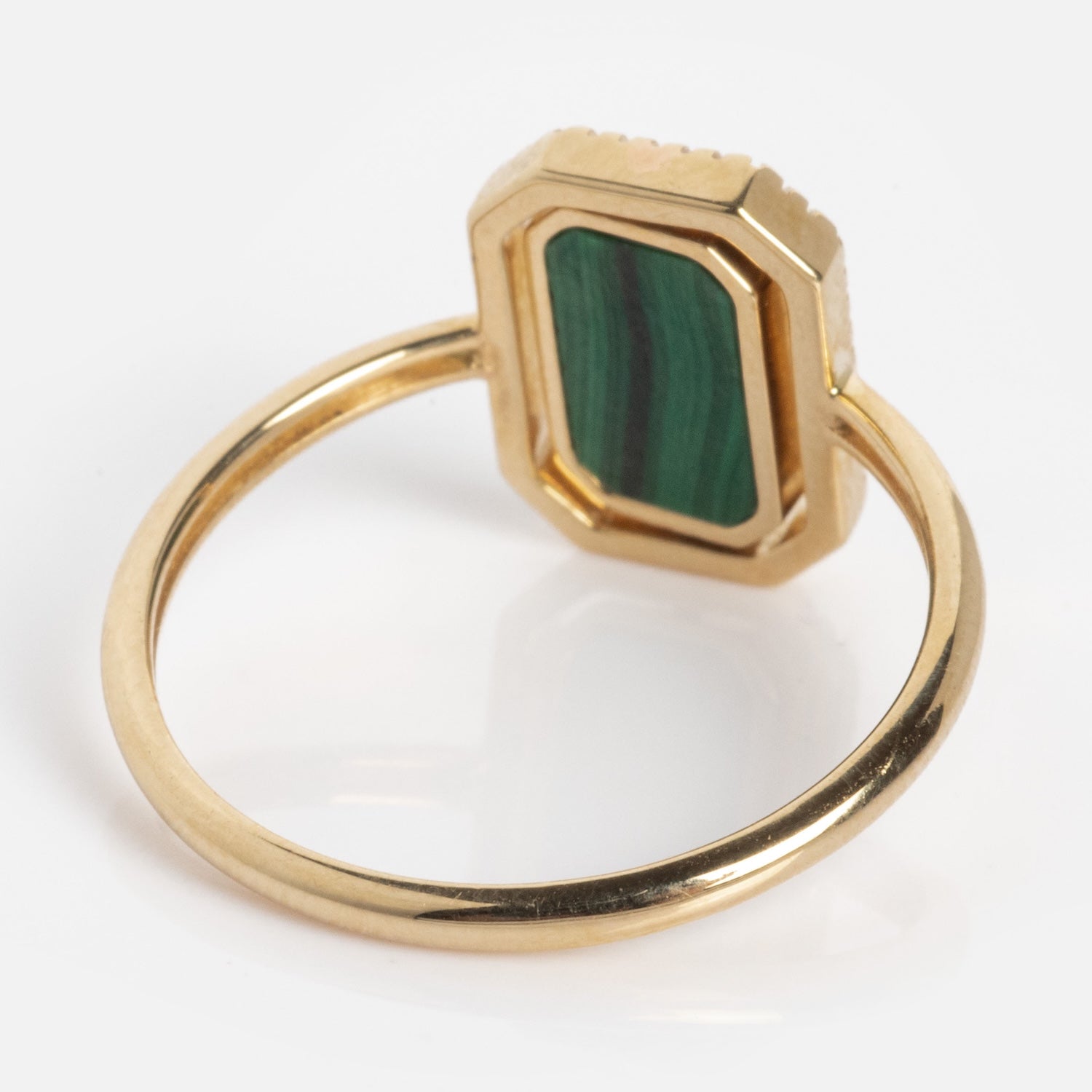 The 10k Gallery Frames Enamel and Malachite Reversible Ring features a thin gold band and a rectangular green malachite stone with dark vertical stripes set in a faceted gold bezel, shown on a white background.