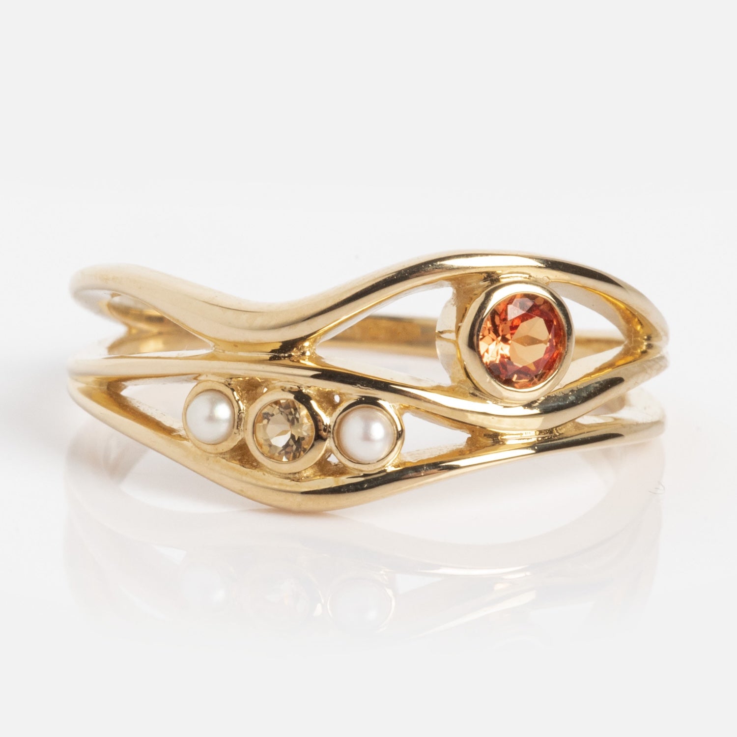The 10k Orange Sapphire and Citrine Bayside Ring features an open, wavy gold band adorned with one orange gemstone and two small white pearls.