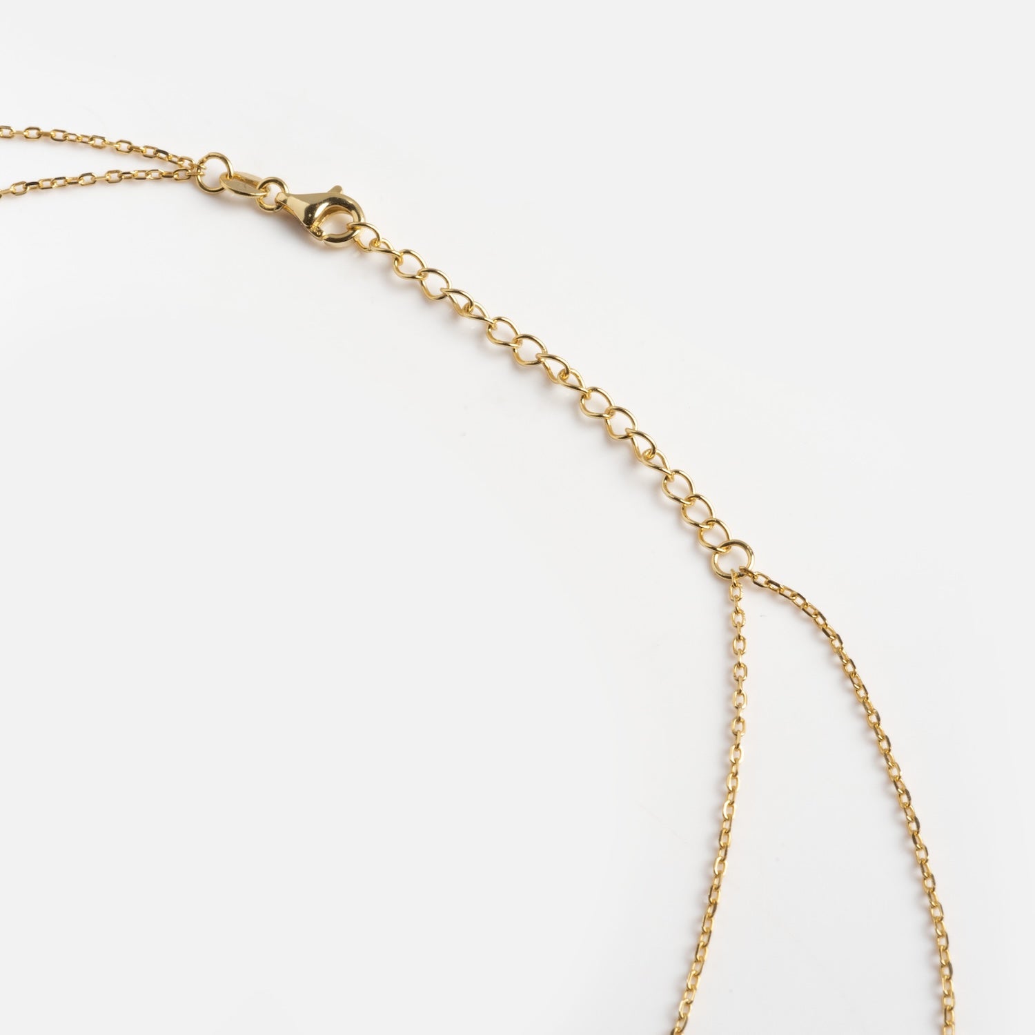 A close-up of the Solitaire Layered Lariat Necklace, featuring a delicate gold chain with an adjustable extension and a lobster clasp, displayed against a white background.