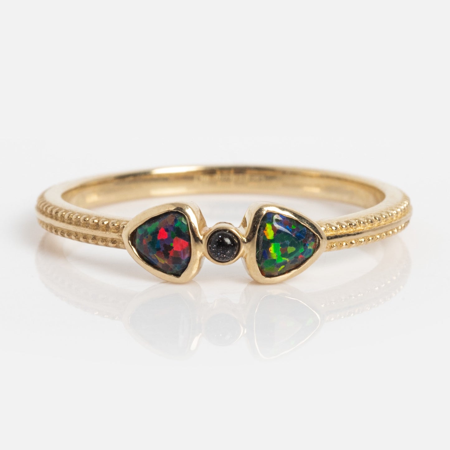 The Solid Gold Black Opal Divine Direction Ring features a gold beaded band with two triangular opals flanking a small round black gemstone, all elegantly set in solid gold.