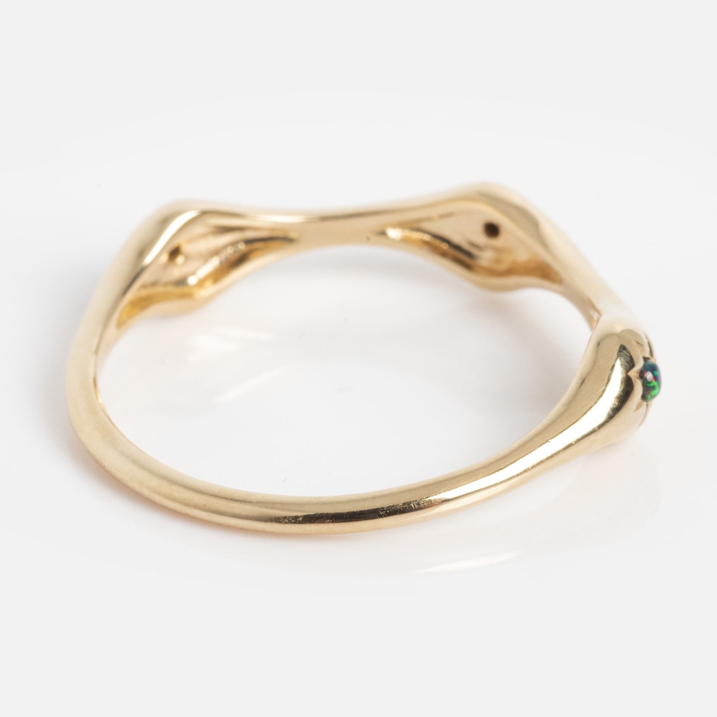 The Solid Gold Black Opal Stars Aligned Ring features a unique, organic shape with gentle curves and a smooth, polished finish. A small black opal accents one end, highlighting its modern and sculptural design.