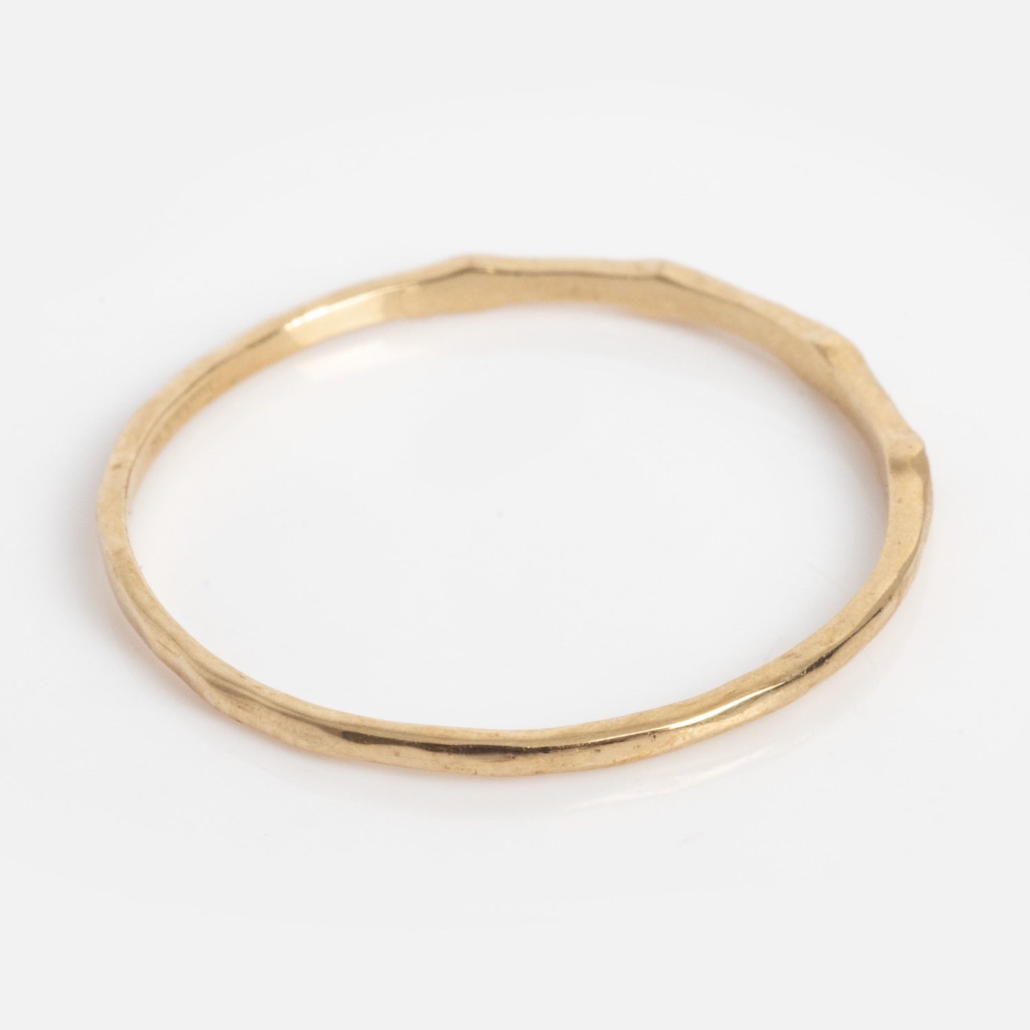 The Solid Gold Dainty Birthstone Stacking Ring features a thin, hammered texture band and is shown against a plain white background.
