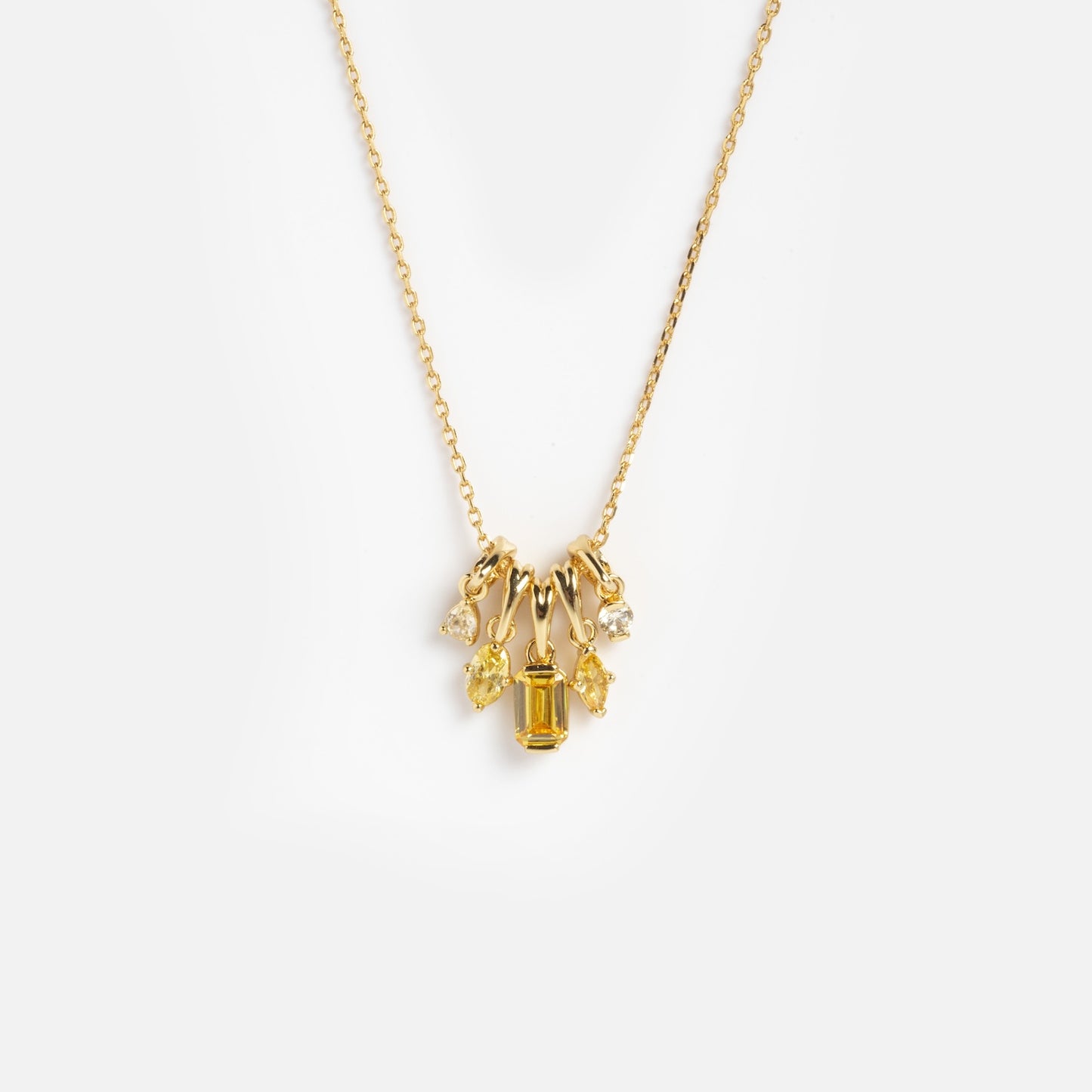 The Shades of You Ombre Birthstone Charm Necklace is a gold chain featuring five small charms—a rectangular yellow gemstone, two clear gems, and two yellow gems in various shapes—shown on a white background.