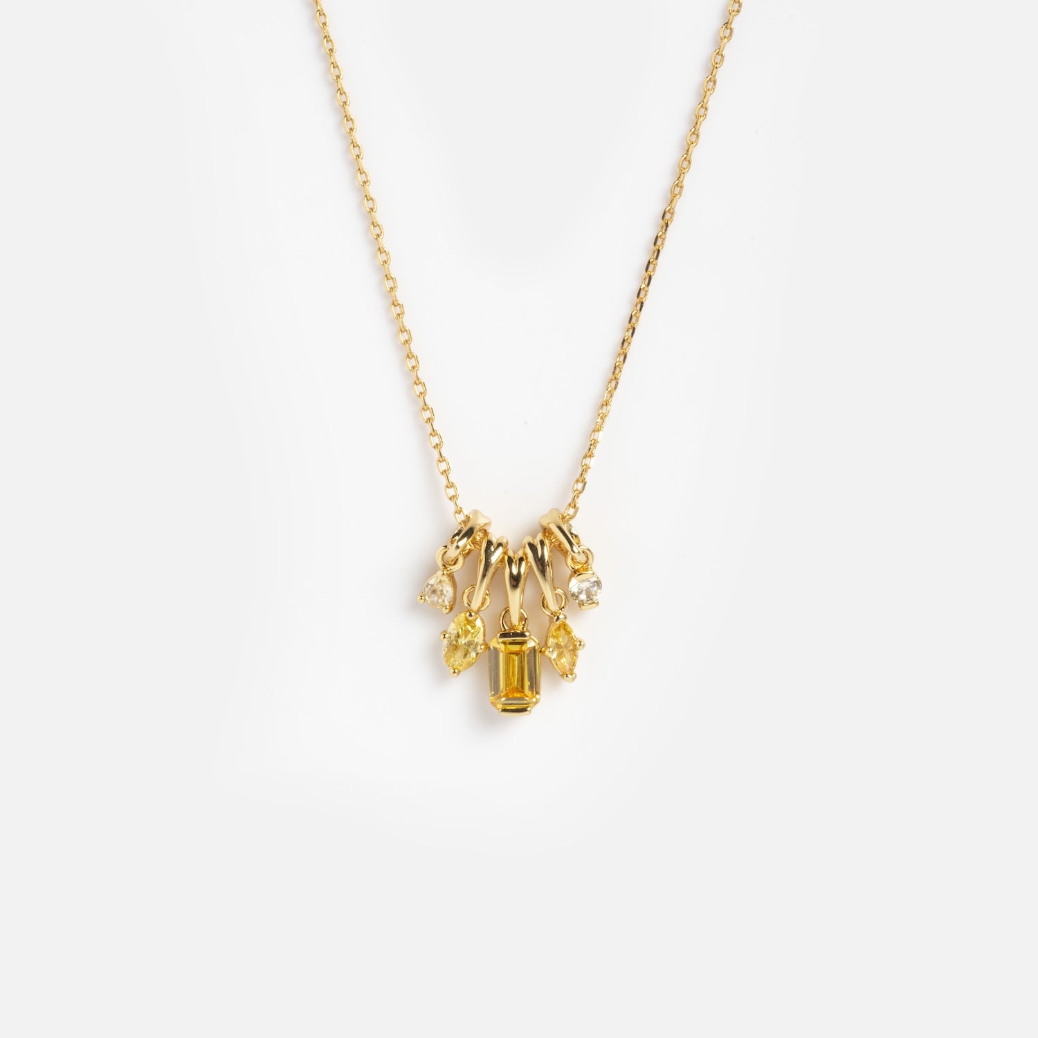 The Shades of You Ombre Birthstone Charm Necklace is a gold chain featuring five small charms—a rectangular yellow gemstone, two clear gems, and two yellow gems in various shapes—shown on a white background.