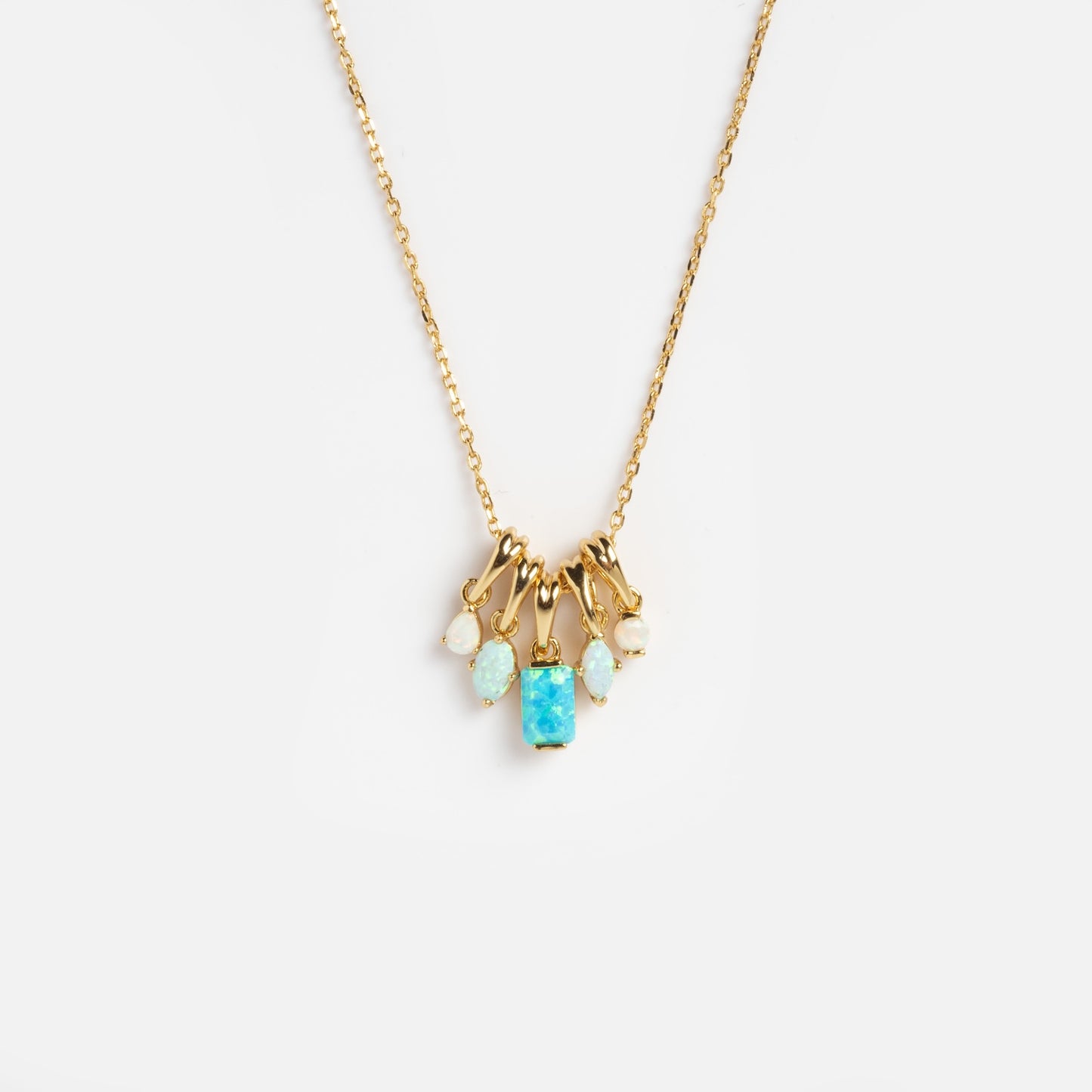 The Shades of You Ombre Birthstone Charm Necklace features a gold chain with five small opal pendants in different shapes, including a central rectangular blue opal, showcased on a plain white background.