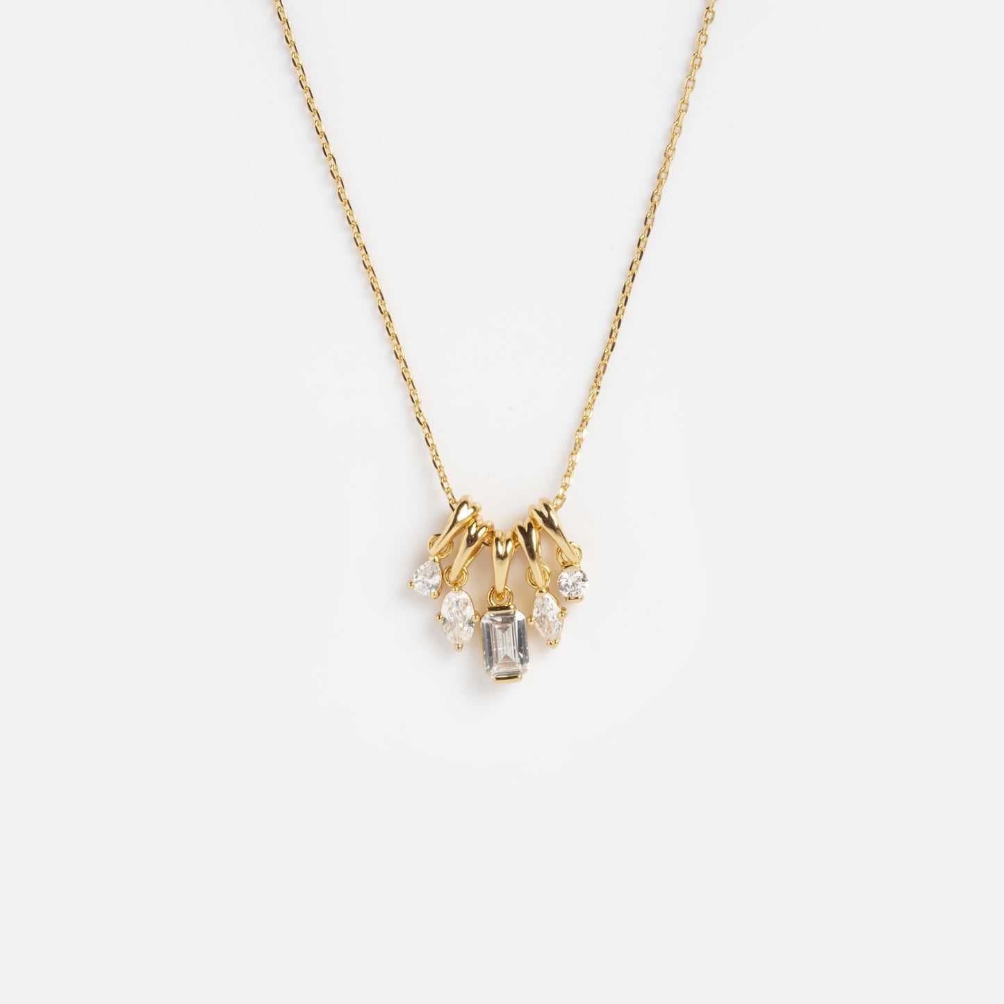 The Shades of You Ombre Birthstone Charm Necklace features a delicate gold chain with five clear gemstones—a central rectangular stone and four round stones—arranged in a symmetrical cluster at the center.