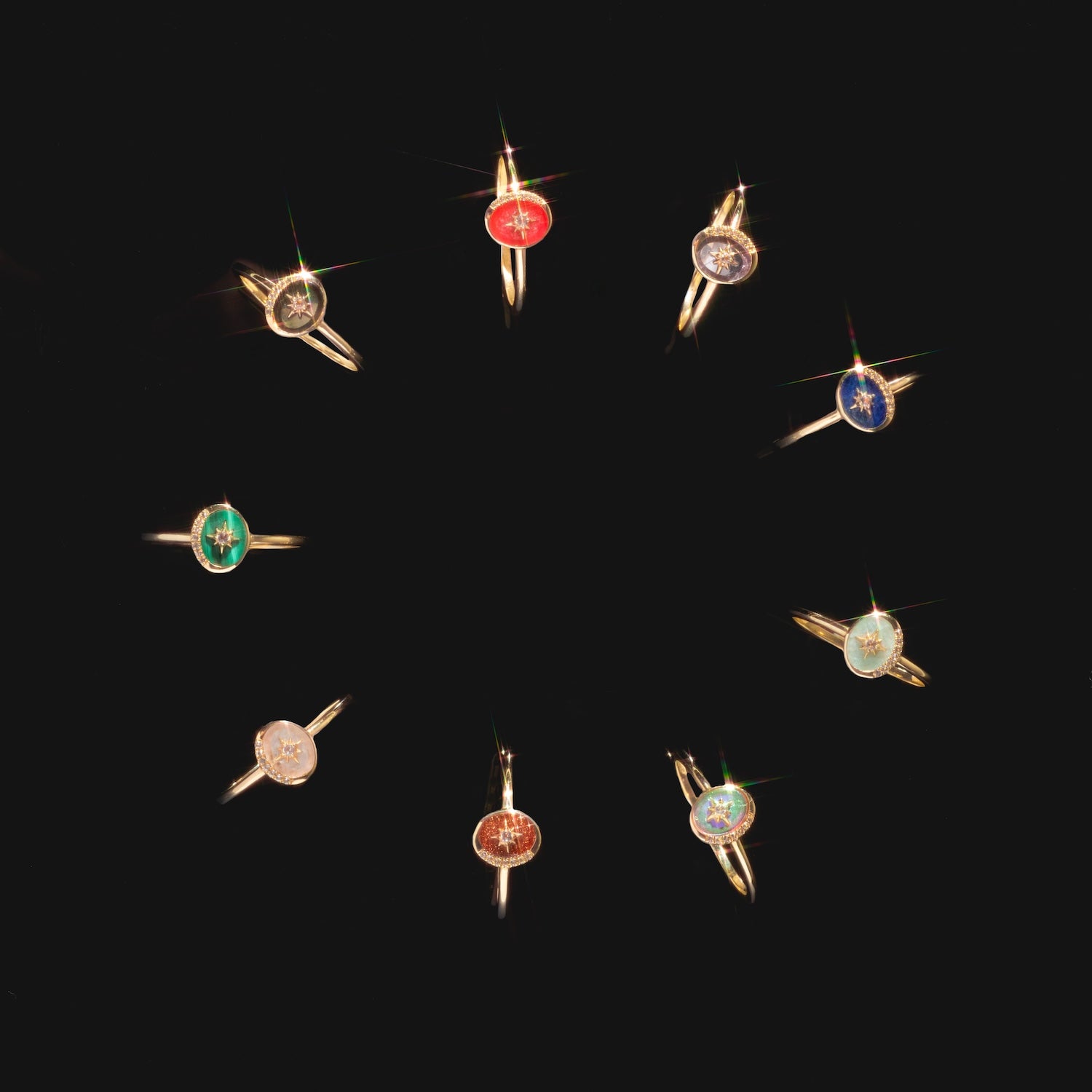 Ten Solid Gold Crystal Crescent Moon Rings for Manifestation, each with a distinct colored gemstone—red, blue, green, and clear crystals—are arranged in a circle on a black background.