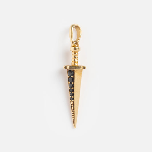 The Solid Gold Amulet Charm is a dagger-shaped solid gold pendant with a textured handle and black stones along the blade, featured as an exclusive against a plain white background.