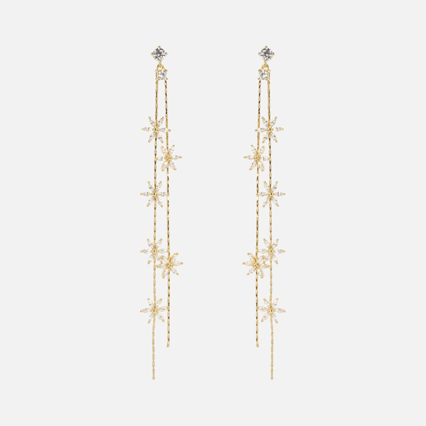 The Whisper Earrings are long, delicate gold earrings with cascading strands and star-shaped designs adorned with small clear crystals, shown on a plain white background.