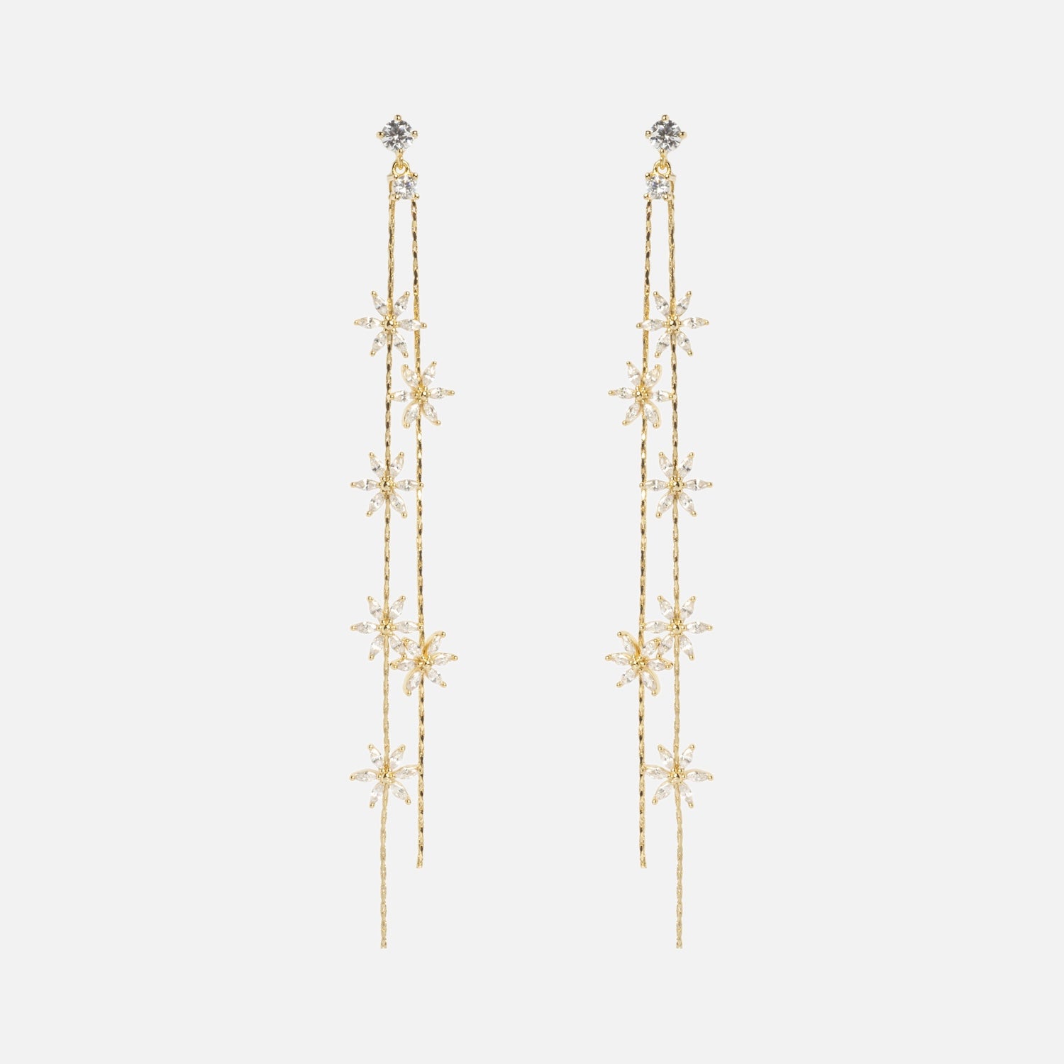 The Whisper Earrings are long, delicate gold earrings with cascading strands and star-shaped designs adorned with small clear crystals, shown on a plain white background.