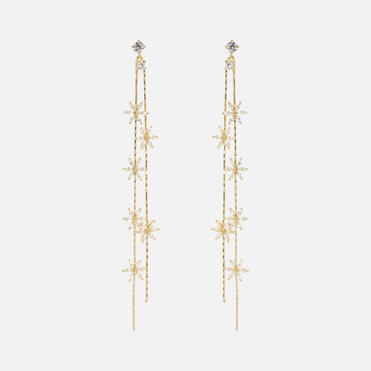 The Whisper Earrings are long, delicate gold earrings with cascading strands and star-shaped designs adorned with small clear crystals, shown on a plain white background.