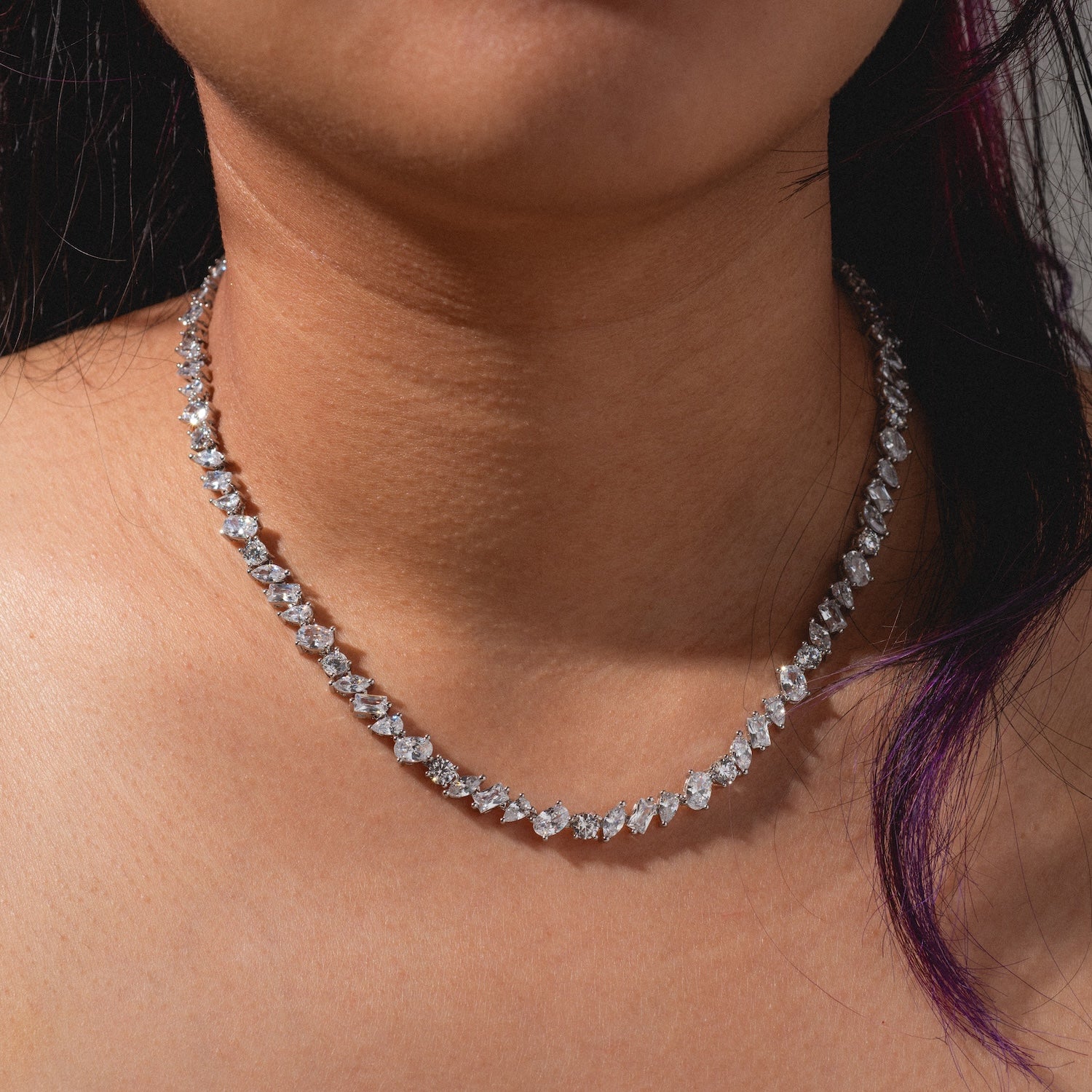 A woman shown from the shoulders up against a neutral background wears the Pear Diamond Tennis Necklace featuring sparkling teardrop-shaped diamonds.