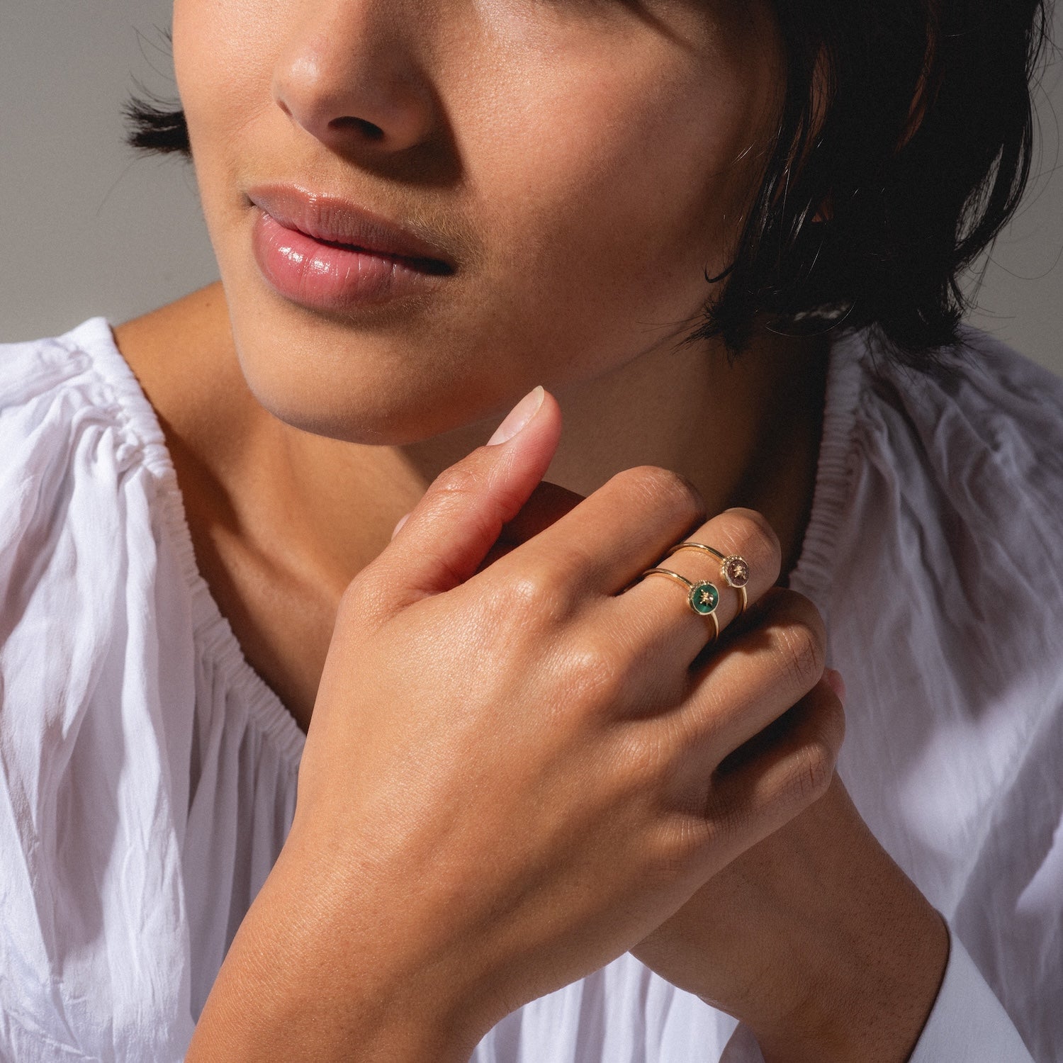 A woman in a white blouse gently clasps her hands, highlighting the Solid Gold Crystal Crescent Moon Ring for Manifestation. Her face is partly visible, with smooth skin and natural makeup.