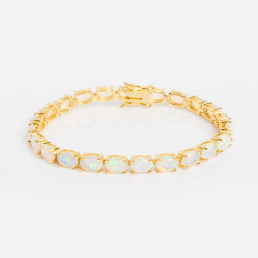 The Eternal Blue Opal Tennis Bracelet is a gold vermeil piece featuring a row of round, iridescent lab-created opals in prong settings, shown on a white background.