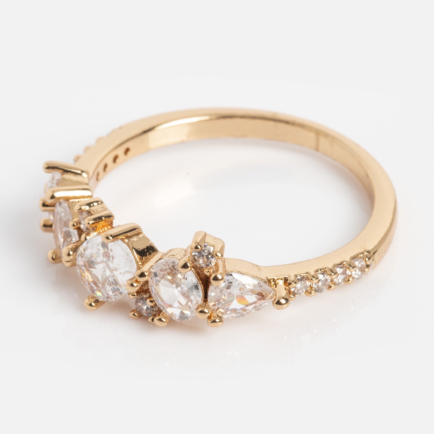 The Statement Crystal Cluster Ring is a gold ring adorned with clear crystals in various sizes, showcasing three prominent oval and teardrop stones at the front and smaller round stones accenting the band.