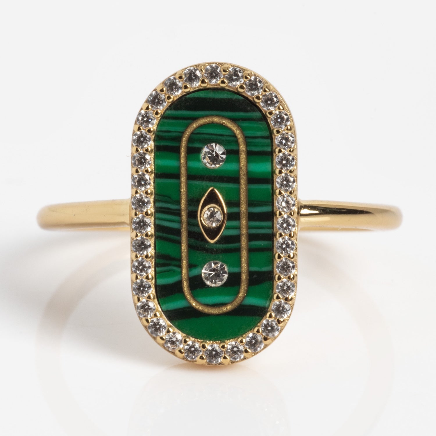 The So Art Deco Cocktail Ring is a gold ring with an oval green malachite inlay, three embedded diamonds, gold accents, and a border of small clear gemstones.