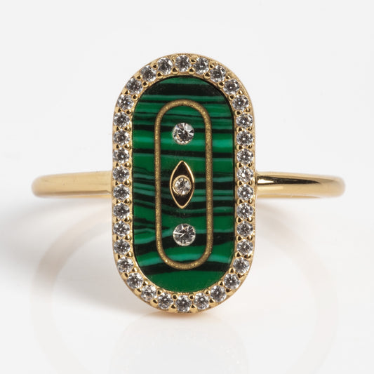 The So Art Deco Cocktail Ring is a gold ring with an oval green malachite inlay, three embedded diamonds, gold accents, and a border of small clear gemstones.