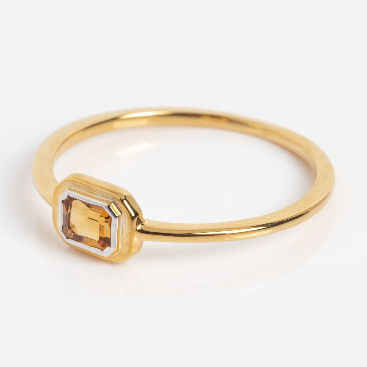 The Matinee Mixed Metal Citrine Ring is a thin gold band with a rectangular, faceted yellow citrine gemstone in a bezel setting, shown on a plain white background.