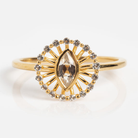 The Silver Screen Starlet Ring features a marquise-cut clear gemstone at its center, framed by a sunburst design and a halo of sparkling round diamonds atop a simple gold band.
