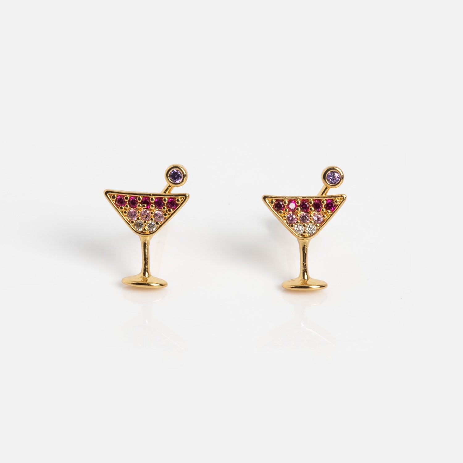 Martini Glass Studs: Gold earrings shaped like cocktail glasses, adorned with pink, purple, and clear gemstones to mimic a drink with garnish. Displayed on a plain white background.
