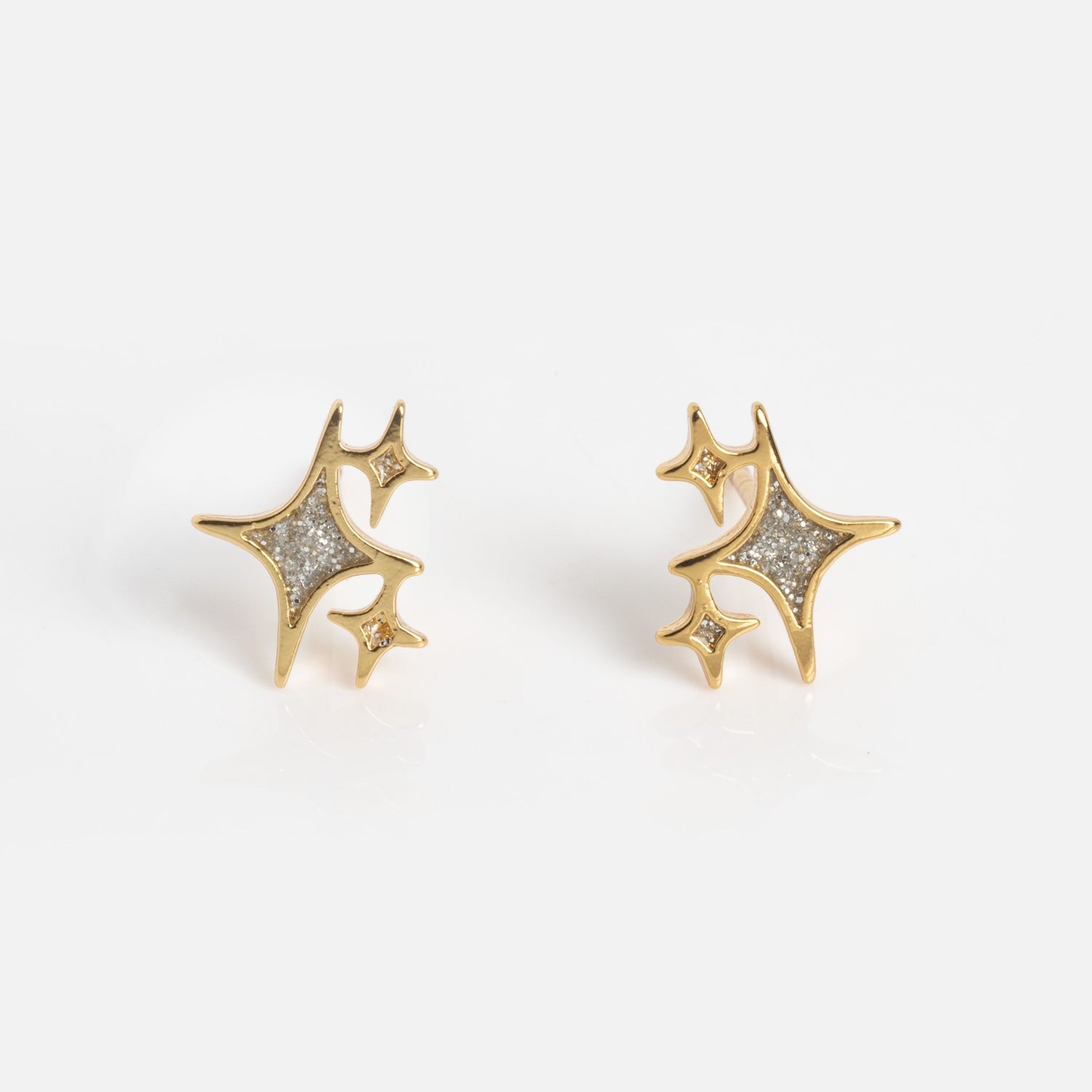 Twinkling Star Studs: gold stud earrings shaped like abstract stars, each accented with small sparkling stones set within the star outlines, presented on a plain white background.