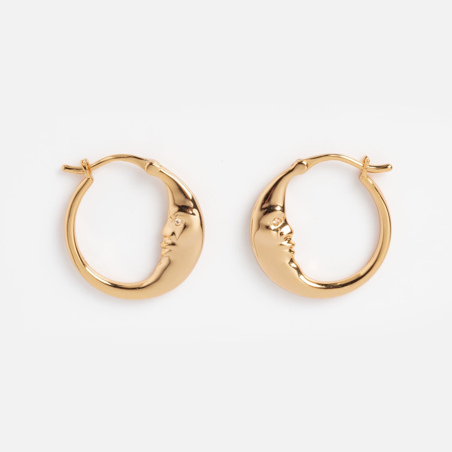 Petite Luna Hoops: Gold crescent moon earrings with sculpted closed-eye faces on each curve, displayed on a plain white background.