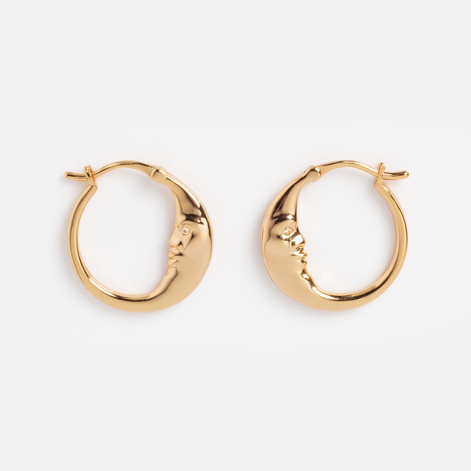 Petite Luna Hoops: Gold crescent moon earrings with sculpted closed-eye faces on each curve, displayed on a plain white background.